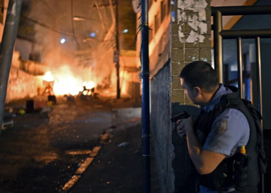 Un polic&iacute;a se cubre durante un tiroteo entre las autoridades y delincuentes en una favela del barrio de Copacabana en Brasil. (Foto: AFP)