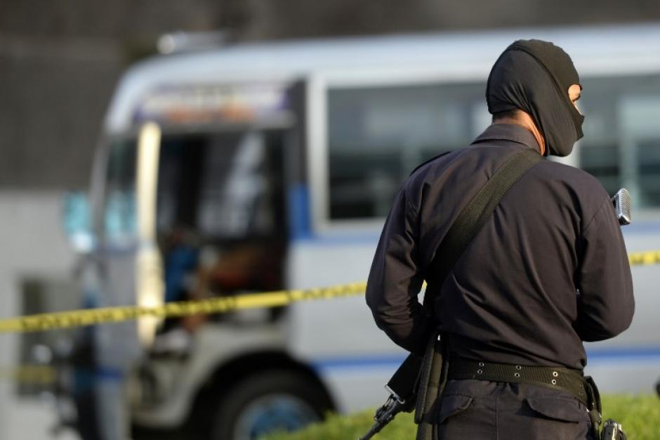 Un polic&iacute;a con el rostro cubierto vigila el lugar donde un conductor falleci&oacute; luego de ser atacado aparentemente por pandilleros. (Foto: AFP)&nbsp;