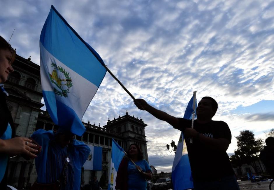 La bandera nacional se confunde con el cielo azul y blanco del amanecer de este 3 de septiembre, d&iacute;a en que Otto P&eacute;rez renunci&oacute; a la presidencia. (Foto: AFP)
