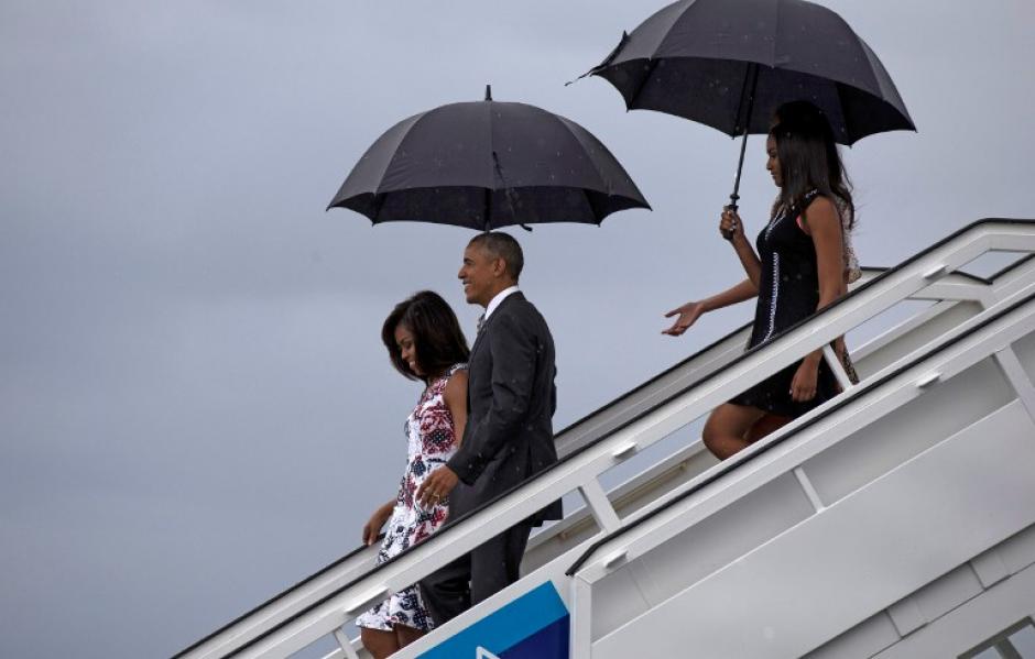 Obama y su familia bajaron del avi&oacute;n presidencial en medio de la lluvia. (Foto: AFP) 