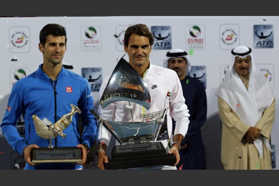 Roger Federer (C) y Novak Djokovic, con sus trofeos de primer y segundo lugar, respectivamente, tras concluir el Abierto de Dub&aacute;i. (Foto: AFP KARIM SAHIB)