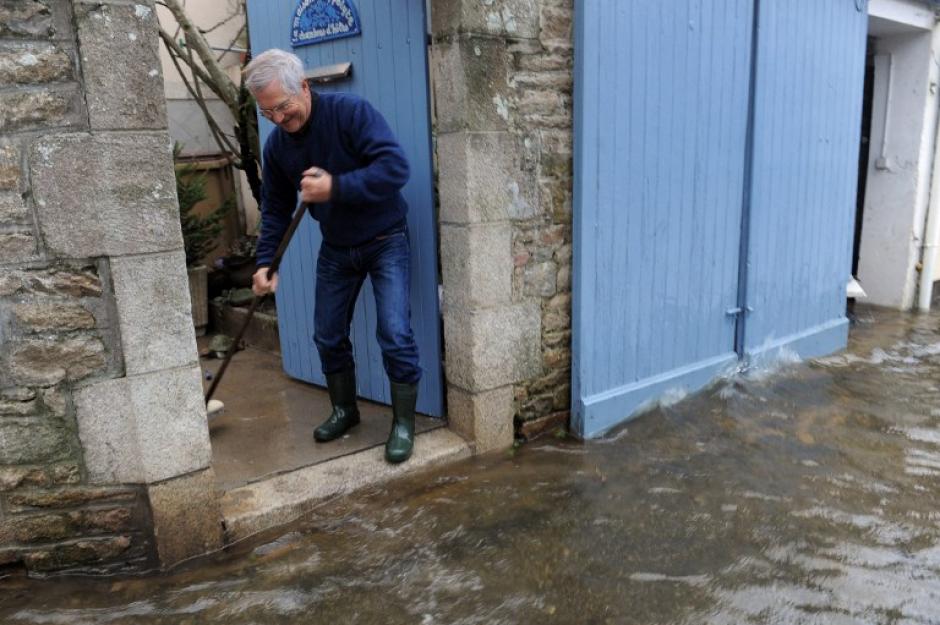 Un hombre limpia la entrada de su casa en Quimperle, oeste de Francia, &nbsp;inundada por el r&iacute;o de Laita. La ciudad est&aacute; bajo alerta por las fuertes lluvias y al alto oleaje de las mareas. AFP PHOTO / FRED TANNEAU