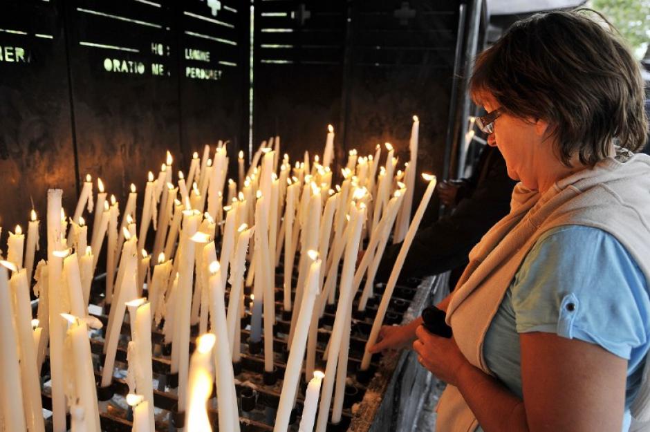 Una mujer sostiene una vela delante de la cueva de Massabielle, donde se dice que la Virgen Mar&iacute;a se apareci&oacute; a Bernadette Soubirous, durante la fiesta de la Asunci&oacute;n.&nbsp;(Foto: AFP/PASCAL PAVANI)