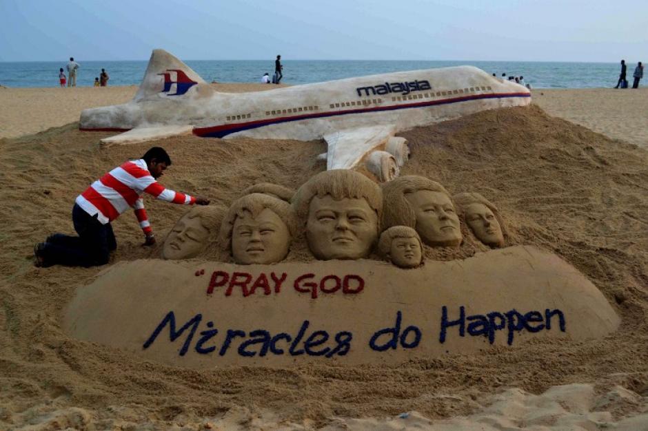 Sudersan Pattnaik, un artista indio, le da los &uacute;ltimos toques a su creaci&oacute;n sobre arena que tiene como motivo enviar el mensaje por las personas que iban abordo del avi&oacute;n de Malaysian Arlines que desapareci&oacute; mientras sobrevolaba el oc&eacute;ano entre Malasia y Vietnam. (Foto: AFP)