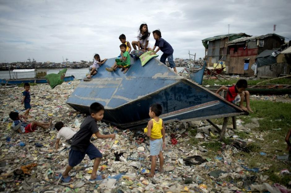 Ni&ntilde;os juegan con una peque&ntilde;a embarcaci&oacute;n que fue arrastrada hasta la villa luego del paso del tif&oacute;n Hagupit en Filipinas. (Foto: Noel Celis/AFP)
