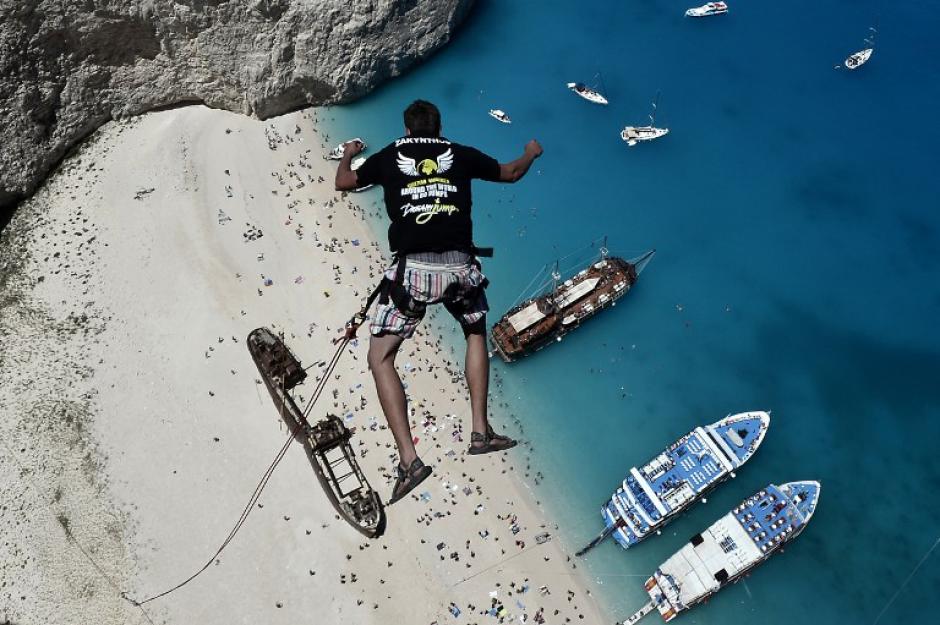 Lukas Michul, miembro del grupo 'Caminante de los Sue&ntilde;os' salta desde lo alto de las rocas escarpadas con vistas a las aguas azules de la playa de Navagio, uno de los m&aacute;s famosos lugares de ocio de la Grecia en la isla tur&iacute;stica de Zakynthos. (Foto: AFP/LOUISA GOULIAMAKI)