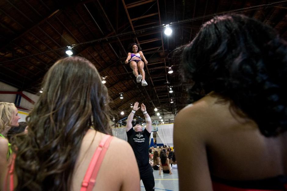 Una animadora aspirante practica un truco mientras otras esperan, durante el primer d&iacute;a de las pruebas de aptitud para ser parte de las porristas de los Baltimore Ravens en un gimnasio en Batimore, Maryland. (Foto: AFP/ Nicholas KAMM)