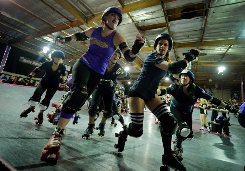 Los miembros del equipo de las Sirenas (uniforme azul) compiten contra los Brawlers Varsity (uniformes p&uacute;rpura) durante las mujeres de LA Derby Dolls pista depositada evento roller derby en Los Angeles. (Foto: AFP/MARK RALSTON)