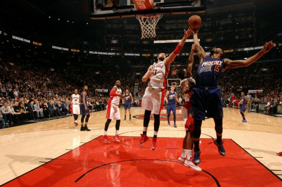 Jonas Valanciunas de los Raptors salta para capturar un rebote y quitarle el bal&oacute;n a Marcus Morris de los Suns de Phoenix. (Foto: AFP)