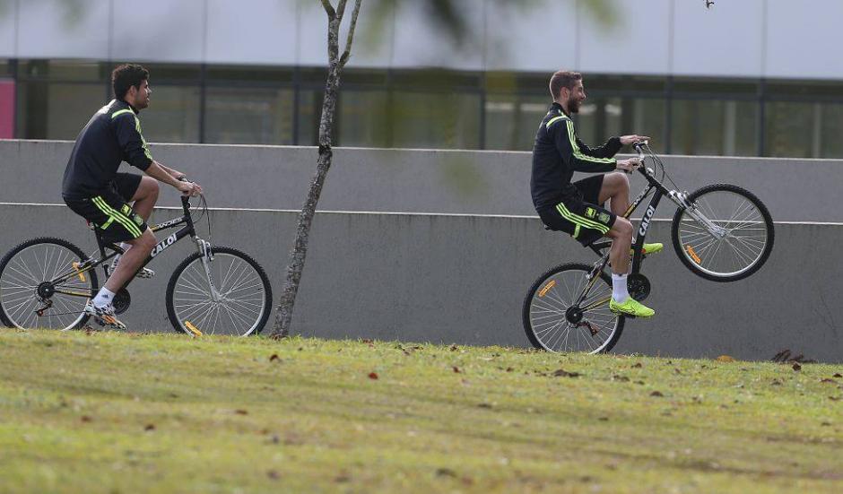 Diego Costa y Sergio Ramos se pasean en bici en el centro de entrenamiento en Curitiba. Ramos hace un "caballito" en la bici. (Foto: El Pa&iacute;s)