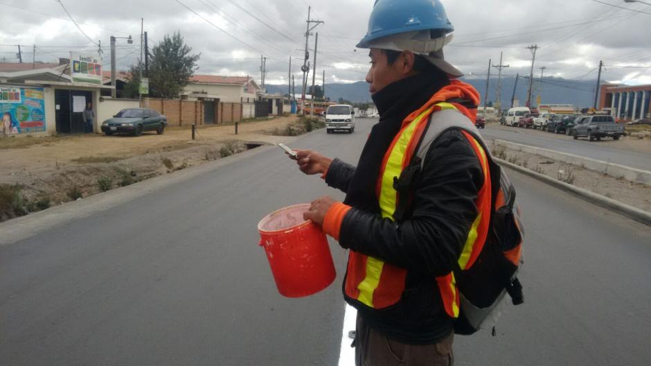 El ingenio y las ganas de salir adelante, hicieron que dos j&oacute;venes encontraran la manera de ganarse unos centavos pintando las cinta asf&aacute;ltica del Perif&eacute;rico de Quetzaltenango. (Foto: Carlos Gonz&aacute;lez/Stereo100Xela)