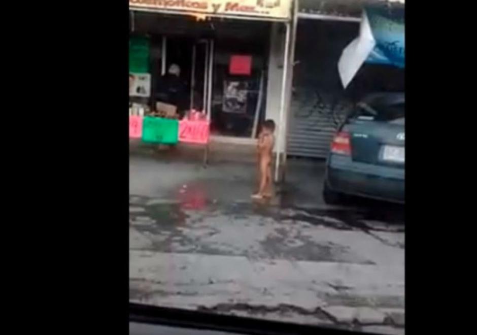 El ni&ntilde;o est&aacute; desnudo parado en un charco de agua, se cree que fue ba&ntilde;ado en la v&iacute;a p&uacute;blica. (Foto: captura de pantalla)&nbsp;
