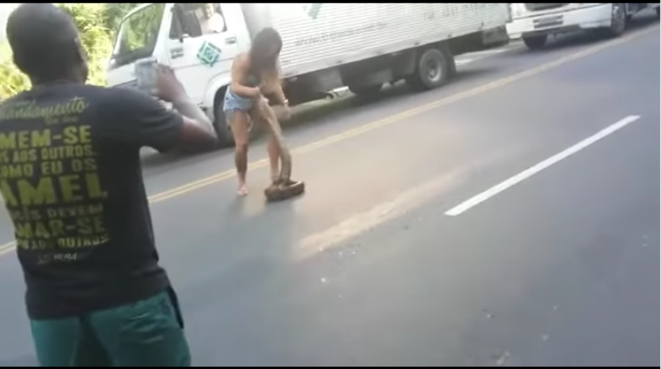 La arriesgada mujer se arriesg&oacute; para remover a la anaconda de la carretera. (Captura Youtube)