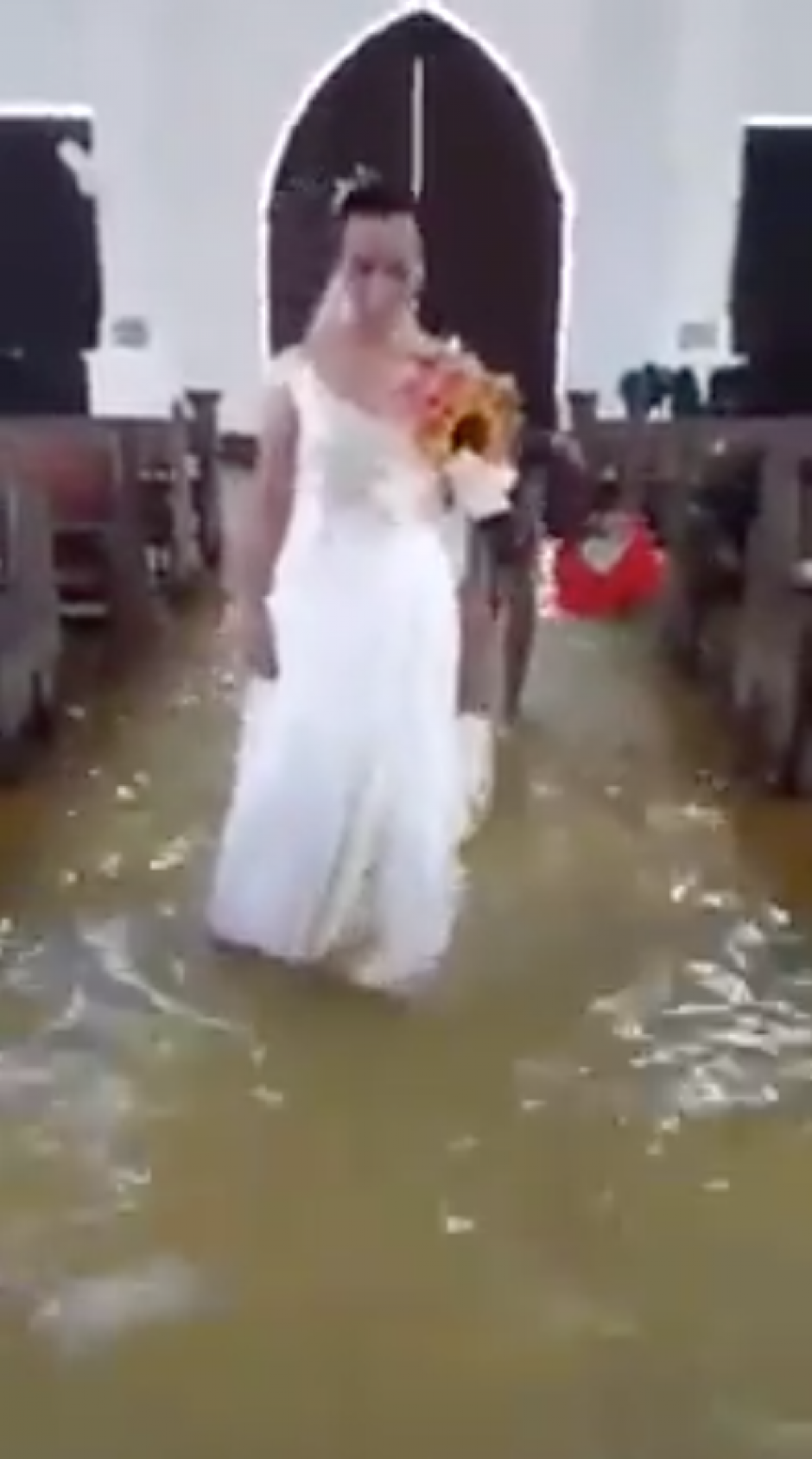 La novia camin&oacute; en medio de la iglesia inundada, su pareja la esperaba y juntos con el agua hasta los tobillos llegaron al p&uacute;lpito. (Foto: captura de pantalla)&nbsp;