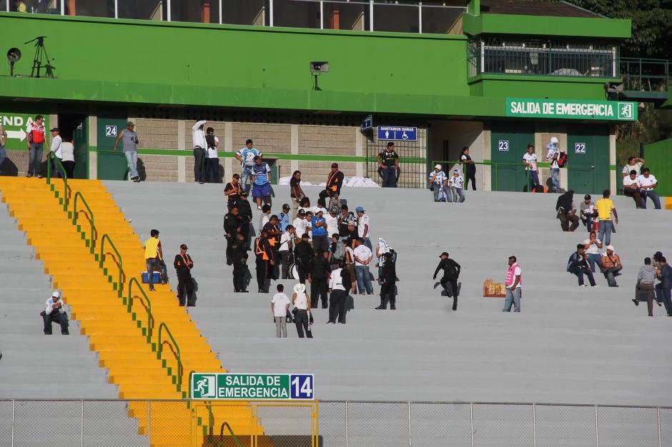 Aficionados de Comunicaciones conversan con agentes de la PNC y seguridad privada en las gradas del estadio Cementos Progreso. (Foto: Fredy Hernández/Soy502)