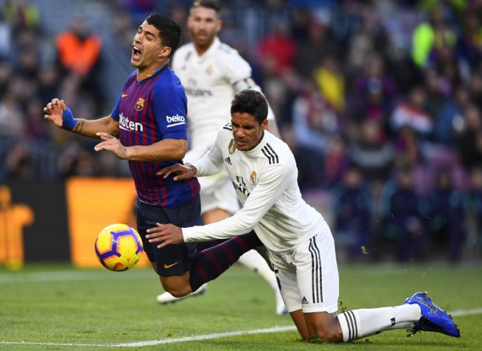 El uruguayo Luis Suárez es derribado por Raphael Varane en el Clásico Español. (Foto: AFP)