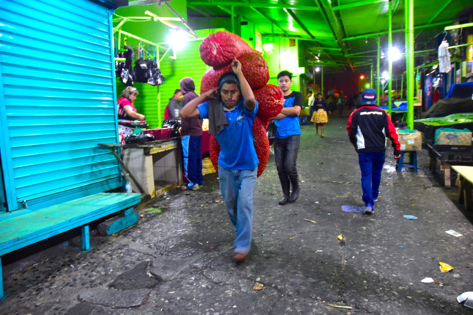 Un cargador lleva a la espalda varios costales con papa dentro del mercado La Terminal durante la madrugada del 3 de abril. (Foto: Fredy Hern&aacute;ndez/Soy502)