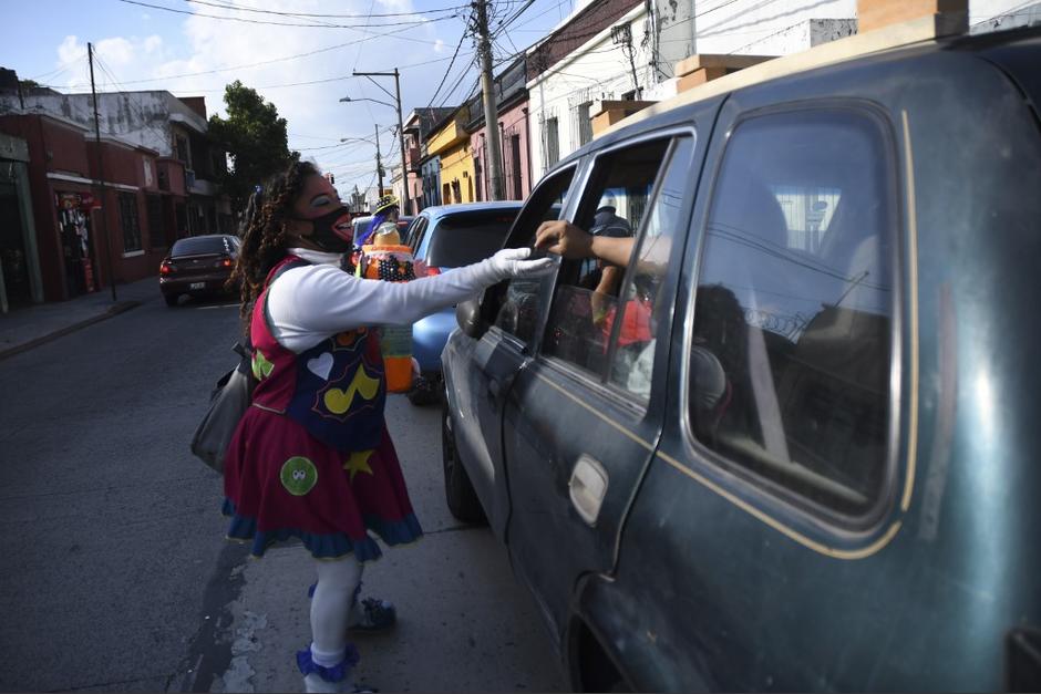 Una payasita recibe un aporte de un automovilista. (Foto: Johan Ordóñez/AFP)