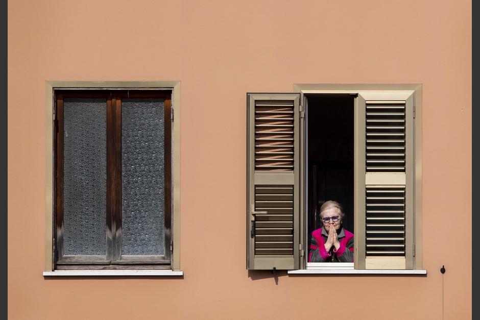 Una mujer reza durante la celebración de una misa a distancia que se celebró en la terraza de una iglesia en Roma. (Foto: AFP)