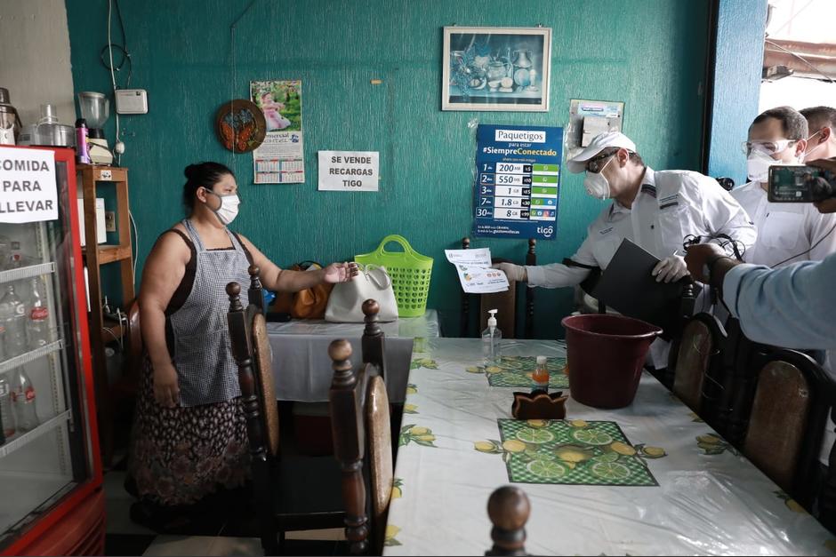 El presidente Alejandro Giammattei entrega un trifoliar con información sobre Covid-19 a una residente de Gualán, Zacapa. (Foto: SCSP)