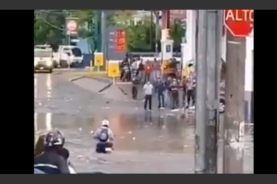 Motorista intenta cruzar una calle inundada, pero retorna a pie