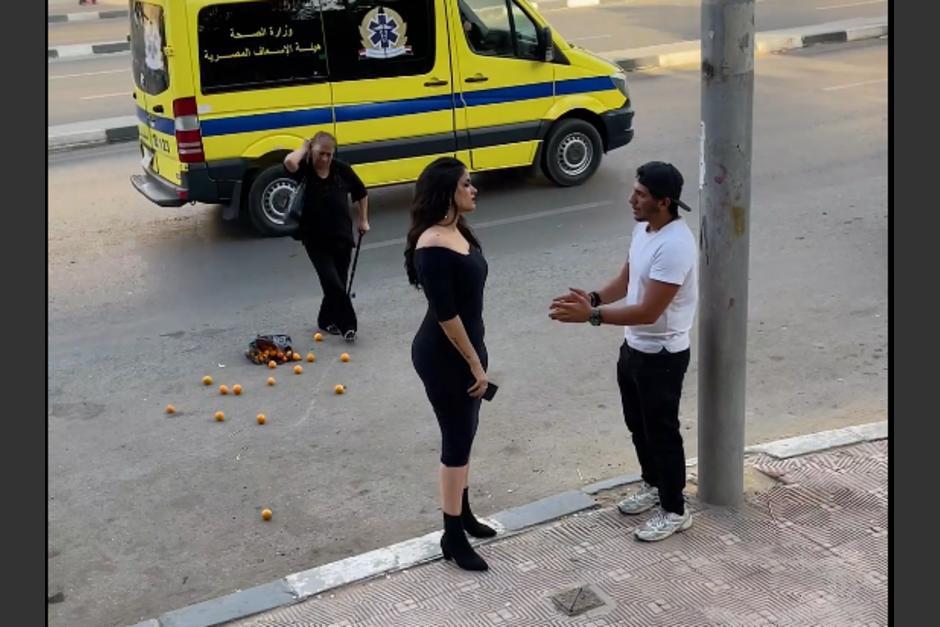 Las escenas muestran a una pareja discutiendo, mientras una mujer bota una bolsa con frutas sobre la calle. (Captura Video)