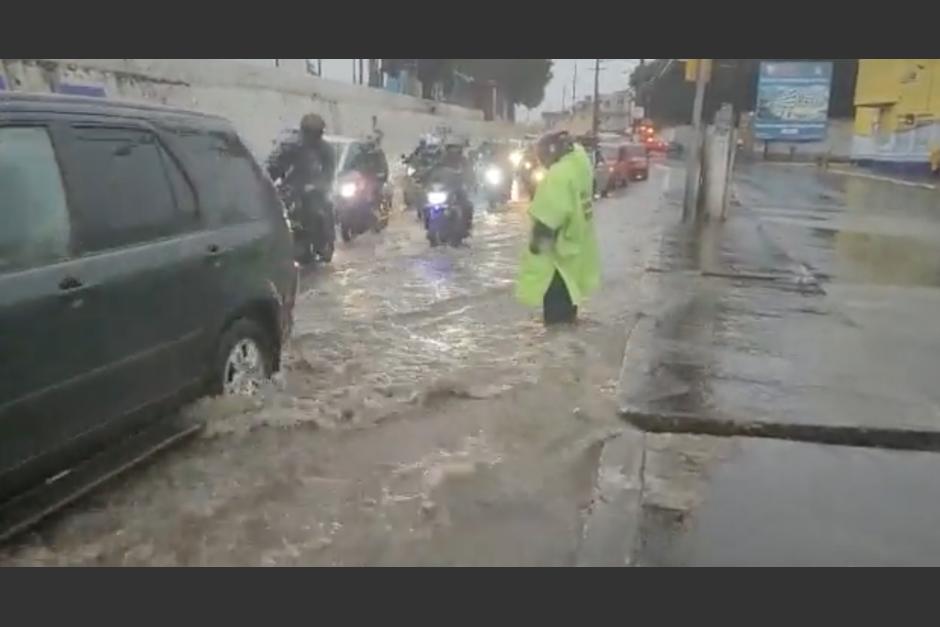 El agente intenta regular el paso en una calle inundada en Mixco. (Foto: Emixtra)&nbsp;