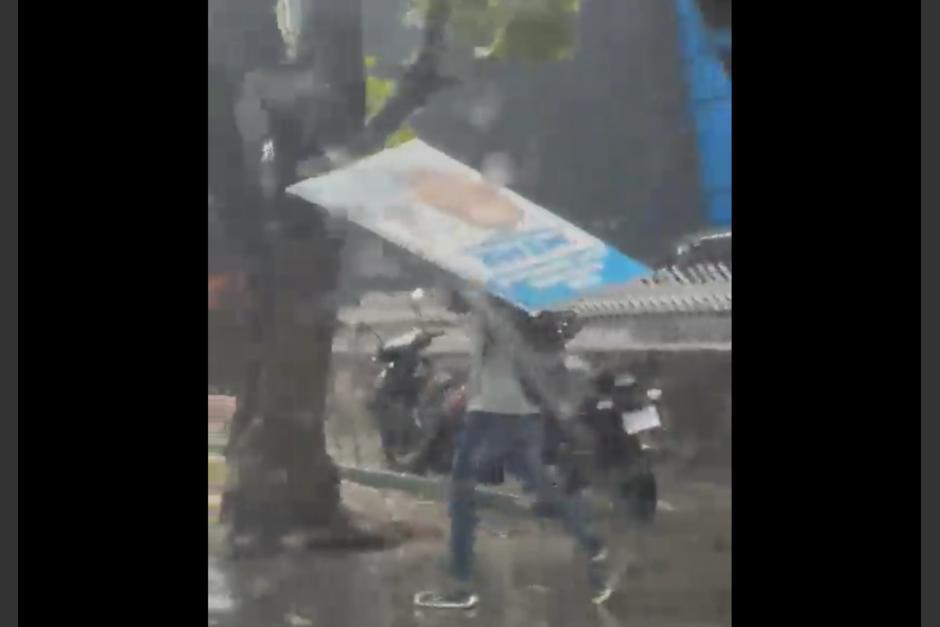 Un guatemalteco se hizo viral tras usar una valla política para cubrirse de la lluvia. (Foto: captura de pantalla)&nbsp;