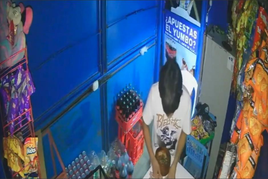 El joven entra por un pequeño espacio y se lleva lo que puede. (Foto: captura de video)