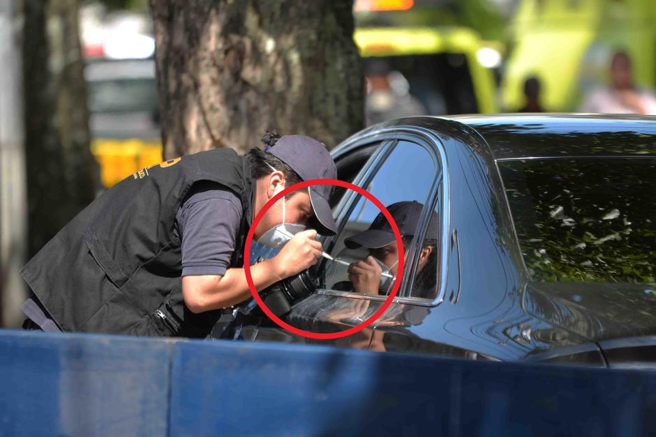 Un técnico en la escena del crimen falla en el protocolo al no utilizar guantes mientras maneja evidencia en el auto del abogado Francisco Palomo, asesinado la semana pasada. (Foto: Jesús Alfonso/Soy502)&nbsp;