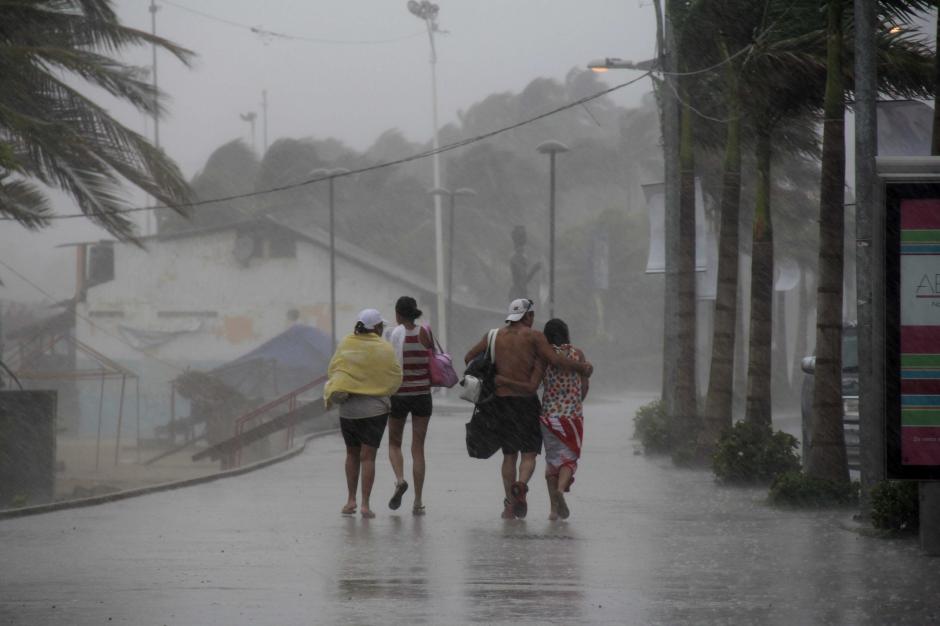 Un grupo de personas camina por una calle en el puerto mexicano de Acapulco hoy, viernes 22 de agosto de 2014, donde se registran fuertes lluvias generadas por la tormenta tropical "Marie" que se desplaza paralela a la costa occidental de M&eacute;xico. (Foto: EFE/Francisca Meza)