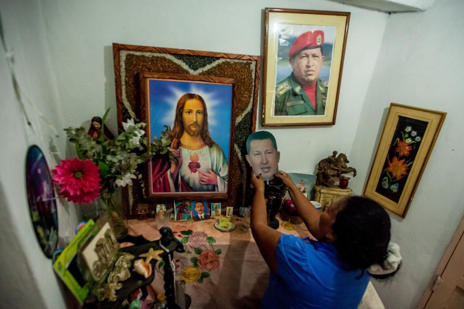 La venezolana Clemencia Linares arrelga una imagen del fallecido Hugo Ch&aacute;vez en el altar religioso en su vivienda, en Venezuela, donde la pol&eacute;mica ahora surge por el uso de la frase "Ch&aacute;vez nuestro". (Foto: EFE)&nbsp;