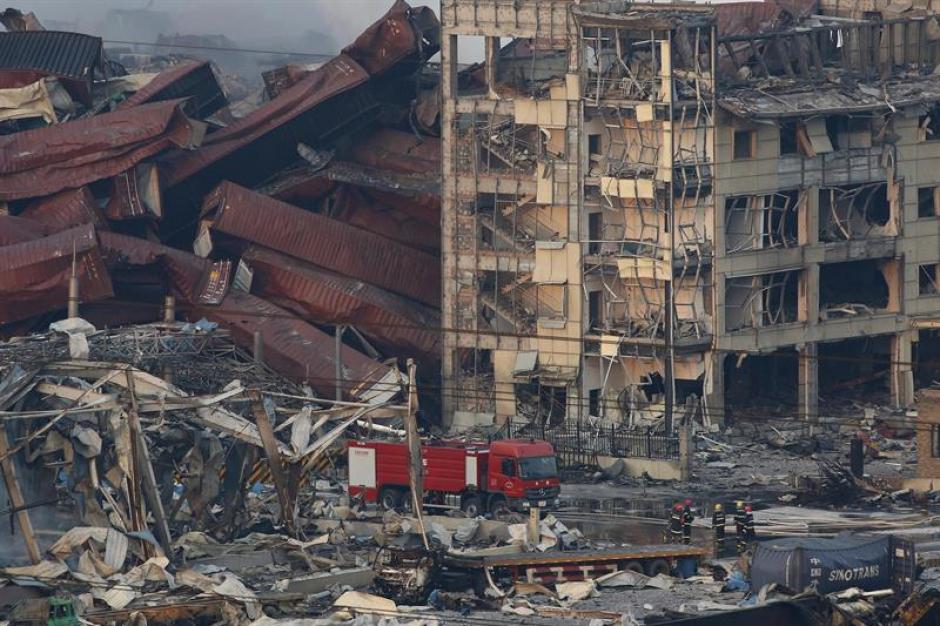 Miembros de los servicios de rescate trabajan entre cientos de veh&iacute;culos quemados y varios edificios destru&iacute;dos tras varias explosiones en China. &nbsp;(Foto: EFE)&nbsp;