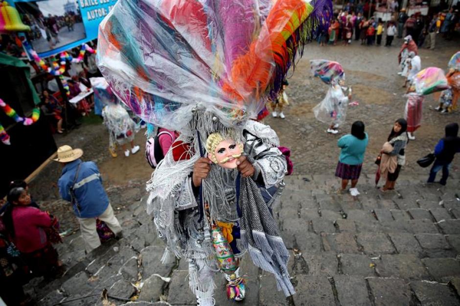 Un hombre sostiene su m&aacute;scara tradicional mientras escala unas gradas en Chichicastenango. (Foto: Esteban Biba/EFE)