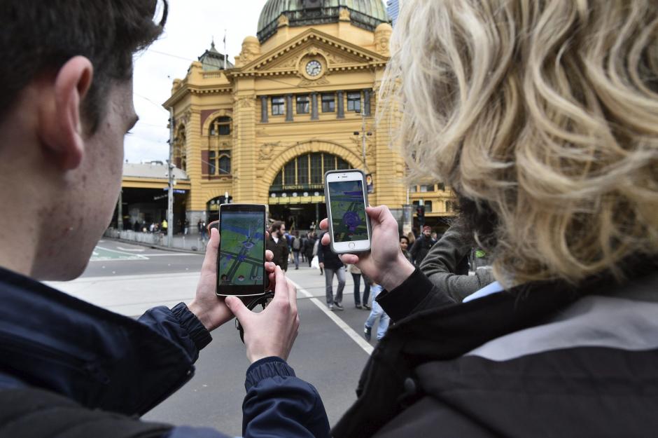 Dos estudiantes prueban el nuevo juego "Pok&eacute;mon Go" en su m&oacute;vil en Melbourne, Victoria, Australia. (Foto:  EFE/Julian Smith)