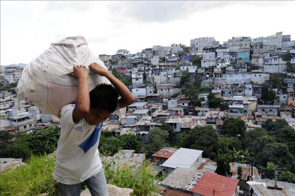 Ismael Gonz&aacute;lez, de 11 a&ntilde;os de edad, carga un saco por un sector del barrio la Limonada, en la Zona 5 de Ciudad de Guatemala, una de las zonas mas pobres de la capital. (EFE)