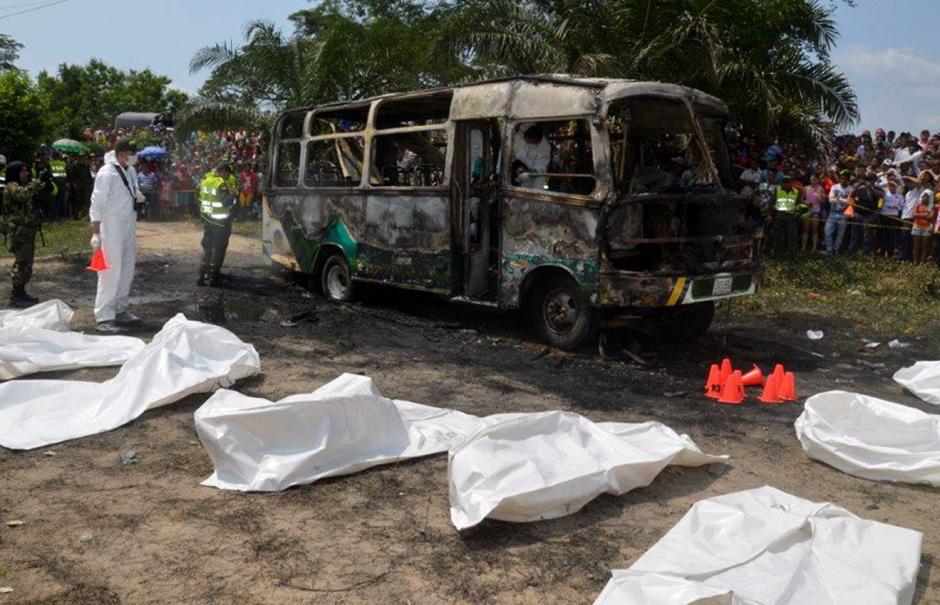M&eacute;dicos forenses hicieron el levantado de cuerpos de los ni&ntilde;os que murieron calcinados tras el incendio del bus que se observa al fondo. (Foto:Efe/El Heraldo)&nbsp;