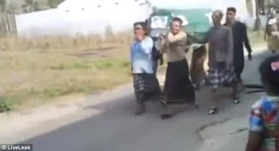 Momento en que los hombres cargan con el ata&uacute;d y el cuerpo a&uacute;n est&aacute; dentro. (Foto: Daily Mail)