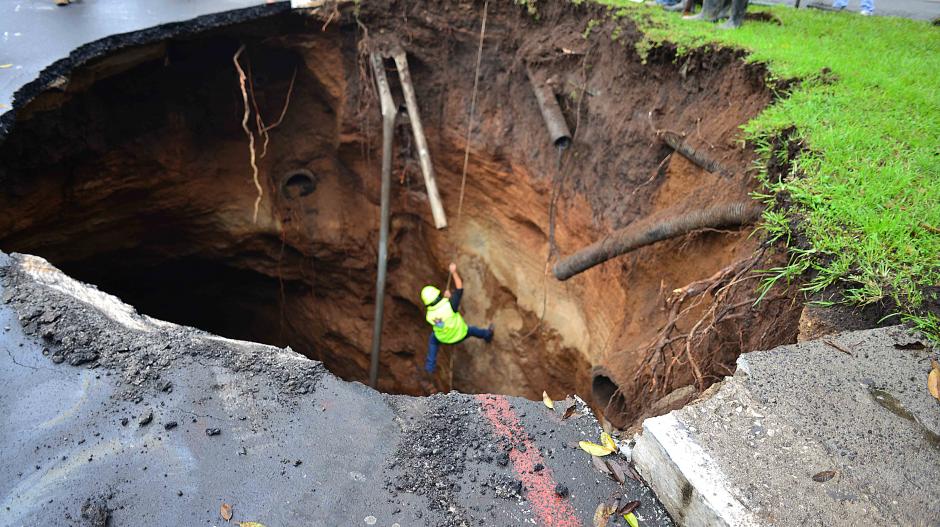 Un empleado municipal desciende por el agujero. En esta toma, se observa que al menos tendría unos diez metros de profundidad. (Foto: Jesús Alfonso/Soy502)