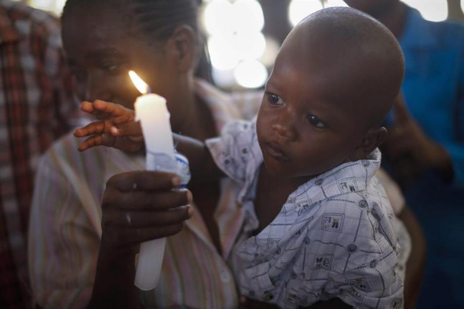 Un ni&ntilde;o keniano mira la luz de la vela en manos de su madre, quien ofrece oraciones por las 147 personas que murieron en un ataque a Garissa University College. &nbsp;(Foto: EFE)&nbsp;