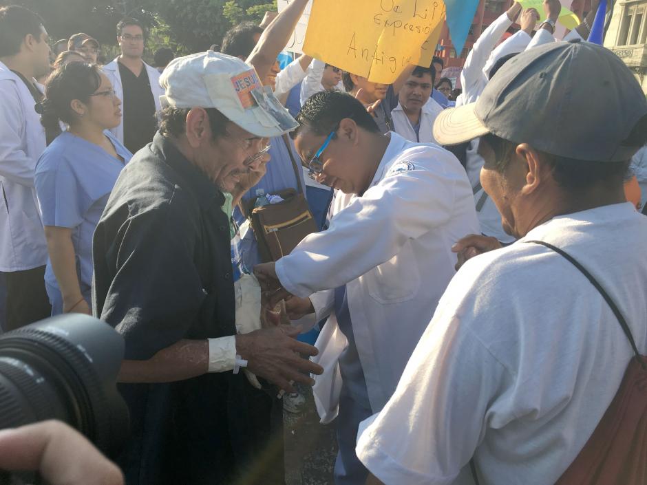 Un m&eacute;dico residente que participaba en la marcha para pedir mejores condiciones laborales, no dud&oacute; en atender a un adulto mayor que necesitaba apoyo en el Parque Central.&nbsp; (Foto: Luis Barrios/Soy502)