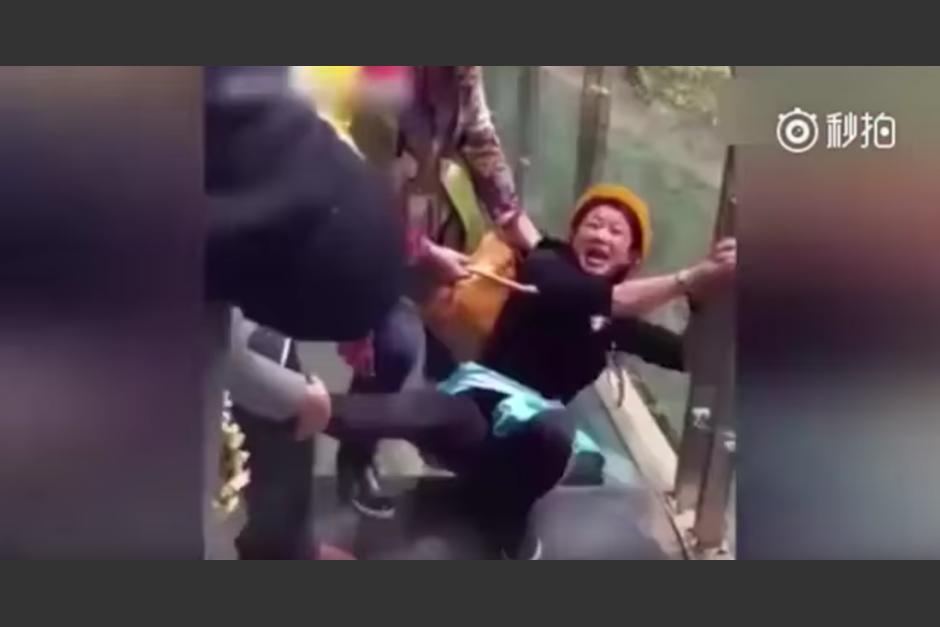 Sus amigos llevan a una mujer a jalones para que pase el puente de cristal. (Captura de pantalla: Man&Women/YouTube)