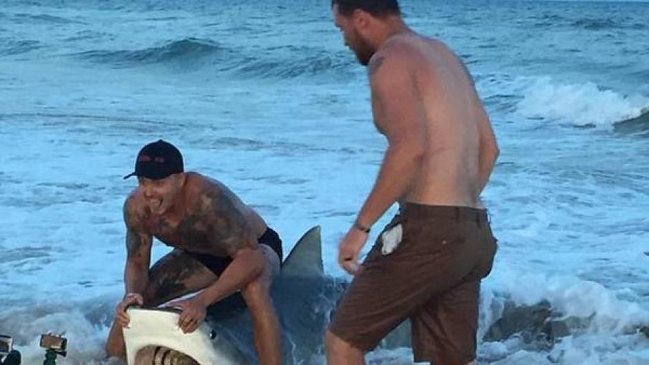 Un hombre le quita un anzuelo a un tibur&oacute;n. (Captura de pantalla: Clarin)