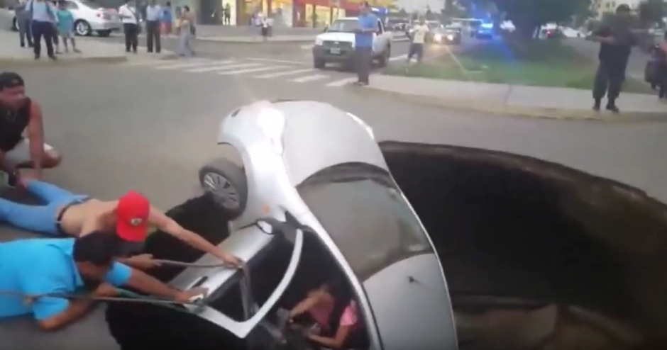 Un grupo de transe&uacute;ntes ayud&oacute; a una pareja de esposos y a su hija de dos a&ntilde;os de edad a salir del veh&iacute;culo en el que viajaban, luego de que ocurriera un hundimiento en una carretera en Per&uacute;. (Foto: Captura de imagen)