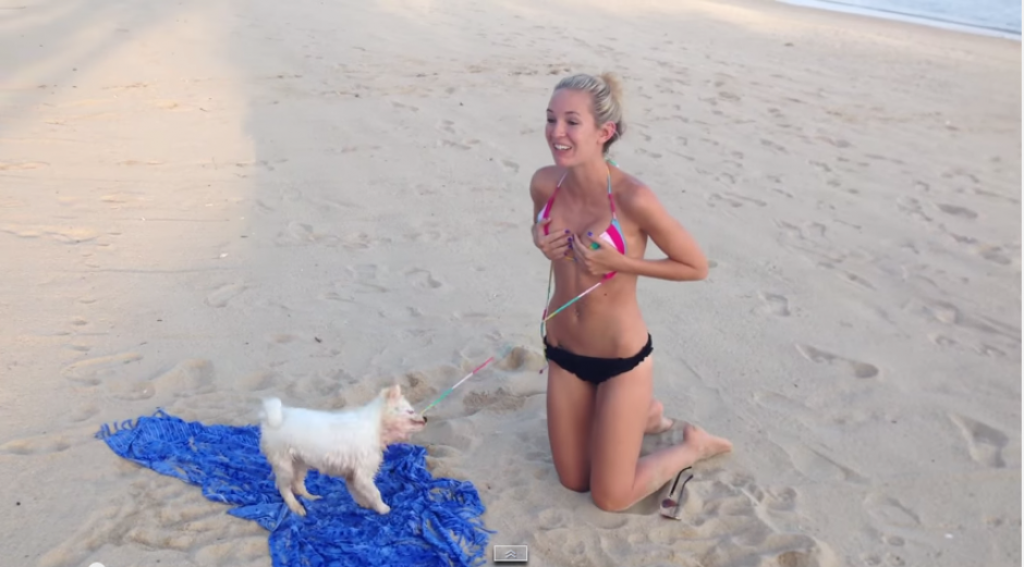 La cantante busca desesperadamente alejarse del perrito que no suelta la cinta de su traje de ba&ntilde;o. El hecho ocurri&oacute; en una playa de California. (Foto YouTube).