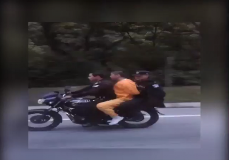 Agentes de la Polic&iacute;a Nacional Civil transportan a un privado de libertad en una motocicleta. (Imagen: tomado de YouTube)&nbsp;