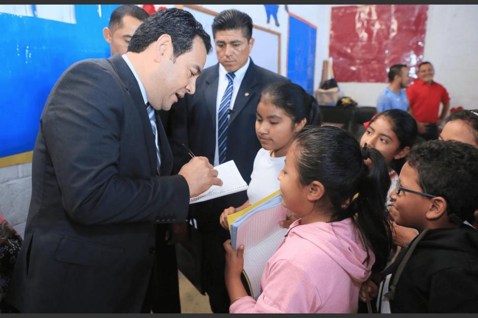 El presidente Jimmy Morales da aut&oacute;grafos a los ni&ntilde;os de la escuela que visit&oacute;. (Foto: Presidencia) 