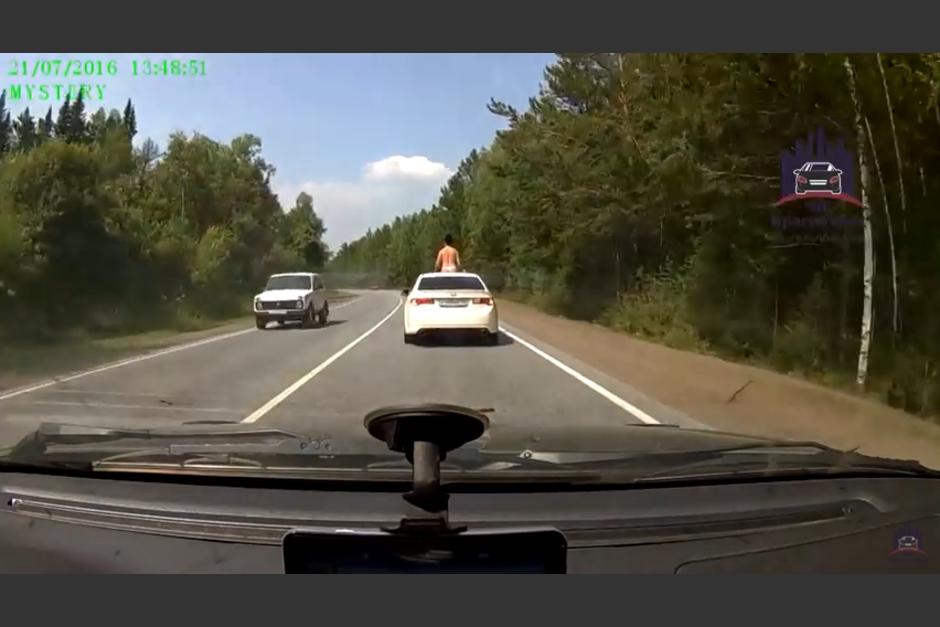 Un conductor grab&oacute; el momento en el que la chica va sobre un carro blanco bronce&aacute;ndose. (Captura Youtube)