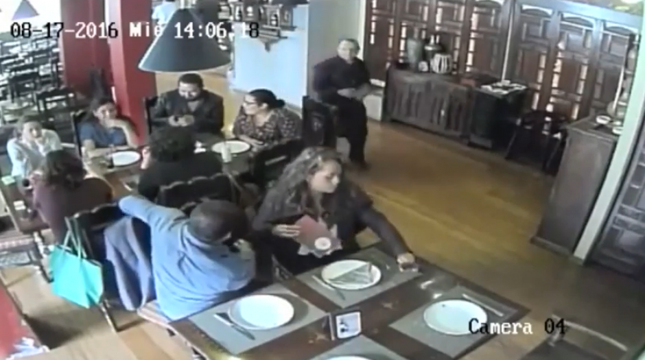 Una pareja se sienta en una mesa cercana a otra donde hay varias personas comiendo y empiezan a observar el panorama. (Imagen: captura de YouTube)