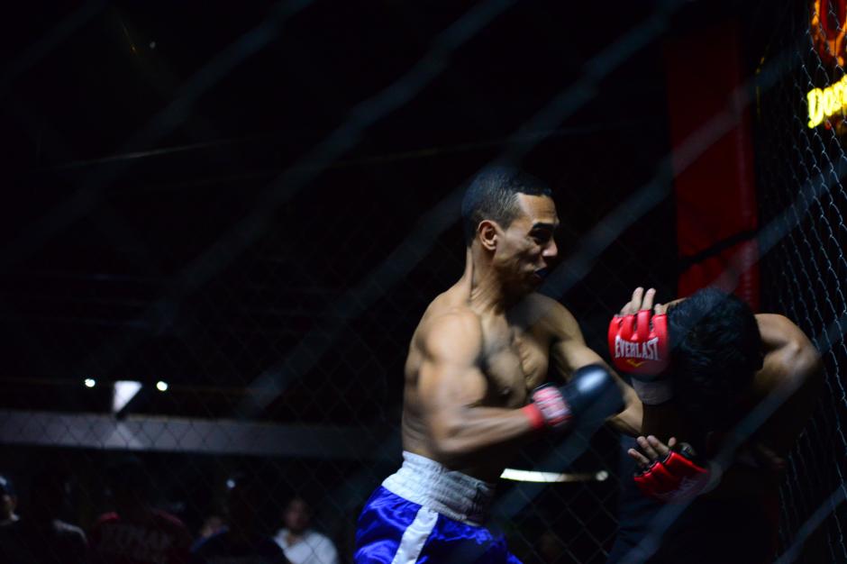    Con un golpe, L&eacute;ster Garc&iacute;a (azul), lleva a la esquina roja a William Rax&oacute;n, durante el encuentro de MMA. (Foto: Wilder L&oacute;pez/Soy502) &nbsp;